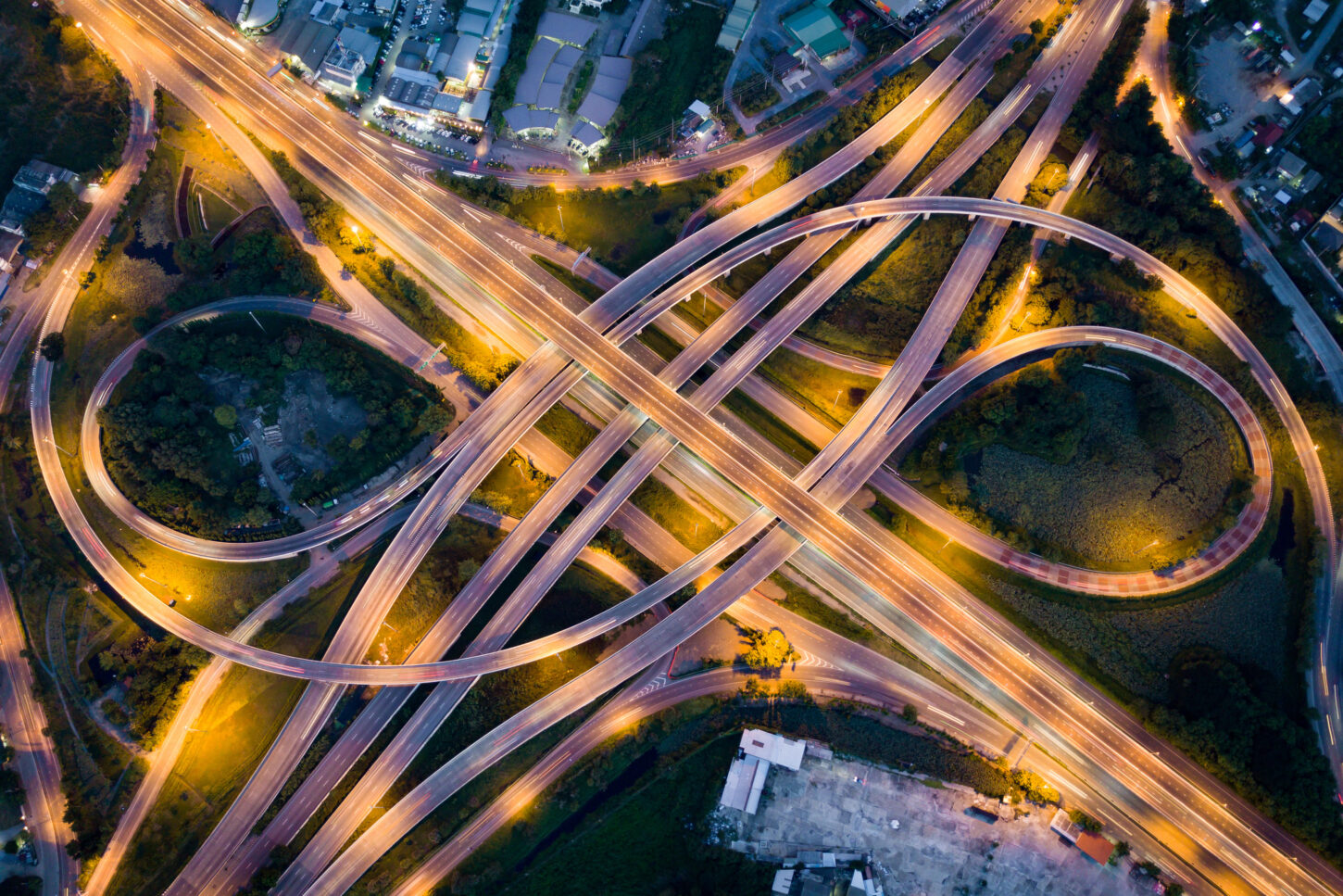 aerial-view-of-illuminated-road-interchange-or-highway-intersection-with-busy-urban-traffic-speeding-on-the-road-at-night-junction-network-of-transportation-taken-by-drone